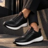 Tenis 3050 Negro Clásico — exterior en clave baja 3 Tenis 3050 Negro Clásico — Sentado · tobillos cruzados