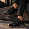 Tenis 3205 Eva Runner Negro con Detalles Miel — exterior en clave baja 3 Tenis 3205 Eva Runner Negro con Detalles Miel — Sentado · tobillos cruzados