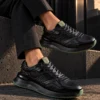 Tenis 3355 Eva Runner Negro con Verde — exterior en clave baja 3 Tenis 3355 Eva Runner Negro con Verde — Sentado · tobillos cruzados